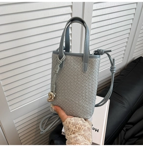 Dettaglio della trama in ecopelle intrecciata di una borsa tote grigio-blu con cuore