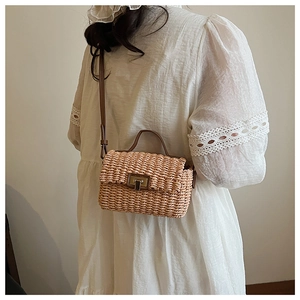 Detail of woven straw crossbody bag with brown leather strap on white lace dress