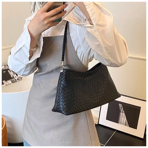 Détail d'un sac à épaule tressé noir avec ferrures argentées et texture cuir