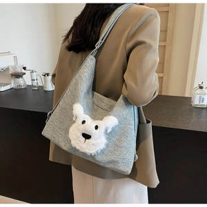 Detail of light blue textured shoulder bag with a plush dog head patch on casual outfit