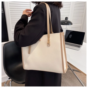 Detail of minimalist cream leather tote bag with contrasting brown handles for workwear
