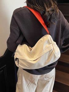 White oversized crossbody pillow bag with vibrant orange strap and ruched design