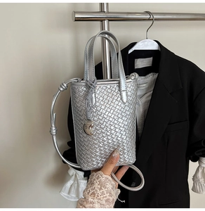 Dettaglio borsa tote in pelle intrecciata argento con ciondolo a perla e artigianalità