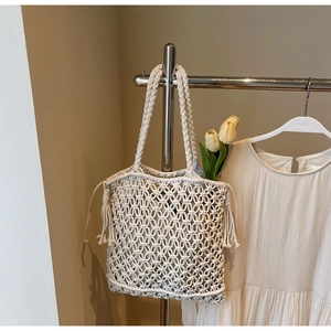 Détail de la texture en macramé crème avec franges décoratives sur le sac de plage