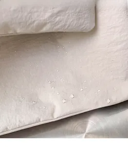 Macro shot of water-resistant cream fabric showing hydrophobic beads on tote bag