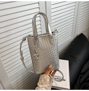 Dettaglio della borsa tote intrecciata argento con finitura metallica e ciondolo a cuore