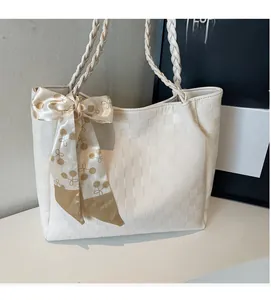 Detail van de gebroken witte geweven shopper met een decoratieve zijden sjaal aan het handvat