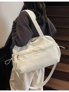 White quilted travel bag with large capacity and shoulder strap worn by a model