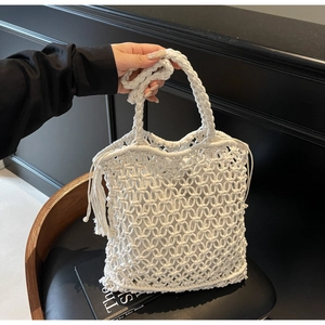 Détail du sac cabas blanc tissé main avec maille évidée et pompons décoratifs