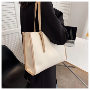 Detail view of a large white commute tote bag with brown trim and adjustable strap