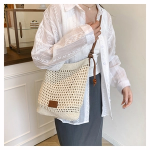 Détail du sac cabas au crochet tissé à la main avec anses en cuir brun et perles en bois