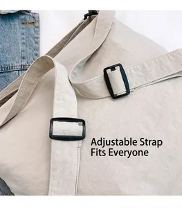 Detail view of adjustable nylon shoulder strap with buckle on beige tote bag