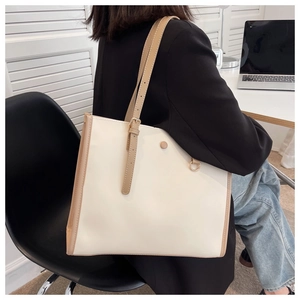 Detail of the cream faux leather tote bag with brown trim and metal buckle on shoulder strap