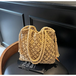 Détail d'un sac cabas tissé à la main avec franges et pompons sur une chaise en cuir noir