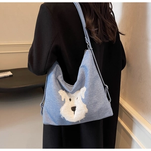 Detail of light blue denim tote bag with white plush schnauzer patch on shoulder