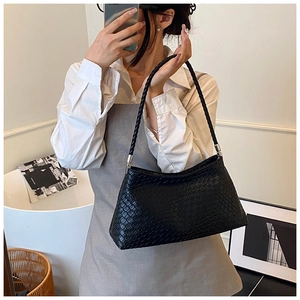 Détail d'un sac à épaule tressé noir avec texture cuir et garnitures argentées