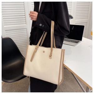 Minimalist beige tote bag with khaki contrast handles shown in an office setting