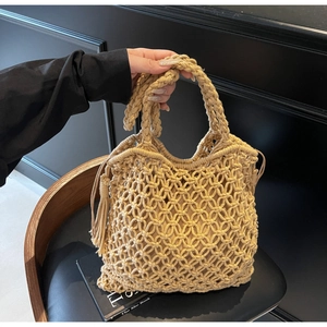 Détail d'un sac cabas au crochet avec texture en maille beige et pompons bohèmes