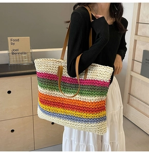 Close-up of a large woven straw tote with colorful stripes and brown leather handles