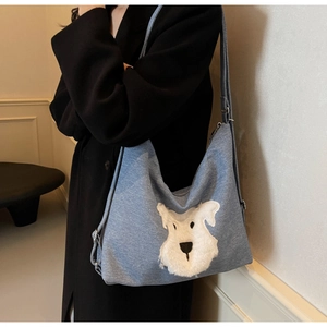 Detail of blue denim hobo bag featuring a cute white plush dog patch on the front