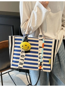 Large blue striped canvas tote bag with lettered straps and a yellow smiley charm