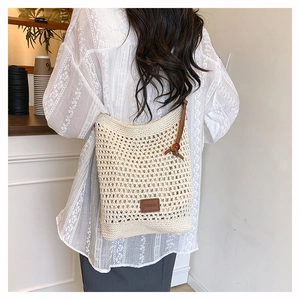 Détail d'un sac cabas tissé à la main avec logo en cuir brun et lanières en perles de bois