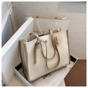 Detail view of large cream and brown tote bag with premium leather texture and packaging