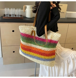 Close-up of colorful rainbow woven straw tote bag with brown leather shoulder straps