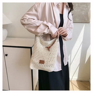 Gros plan d'un sac cabas tissé blanc avec bandoulière en cuir marron sur l'épaule
