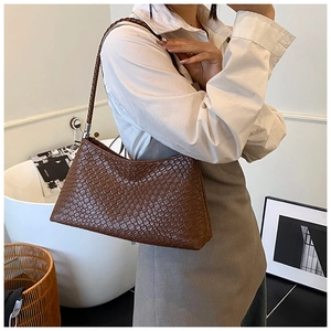 Gros plan du sac à bandoulière marron à texture tressée avec des détails argentés élégants