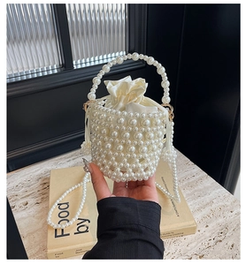 Detail of hand-woven pearl bucket bag with cream satin drawstring lining and elegant handle