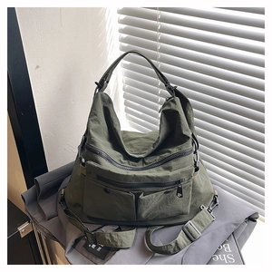 Detail of army green nylon tote bag featuring multi-pocket design and wide shoulder strap