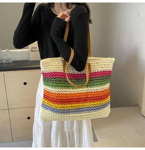 Detailed texture of rainbow woven straw tote bag with brown leather handles
