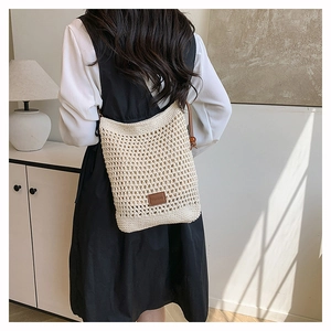 Détail d'un sac bandoulière tissé crème avec étiquette logo en cuir brun et perle en bois