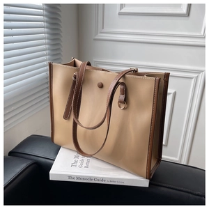 Close-up of contrast stitching and metal ring detail on two-tone leather tote bag