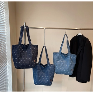 Detailed view of three denim tote bags with white bow patterns in various blue shades