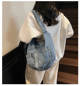 Detail of light blue denim hobo bag with vintage wash and functional side pockets