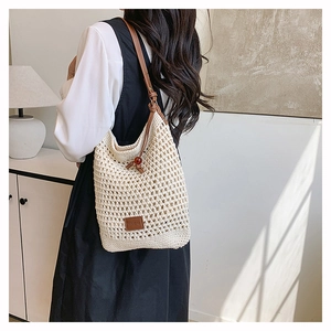 Détail du sac beige tissé à la main avec bandoulière en cuir brun et perle rouge