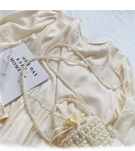 Detailed top view of a cream woven pearl bucket bag with drawstring closure and strap