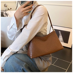 Gros plan sur la texture tressée marron et les détails argentés du sac seau rétro
