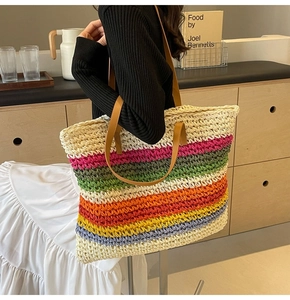 Detail of colorful woven straw tote bag with rainbow stripes and brown leather straps