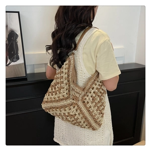 Detail of hollow crochet knit tote bag with brown leather strap and contrast weaving