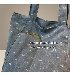 Detail of denim tote bag with butterfly embroidery featuring a functional front pocket