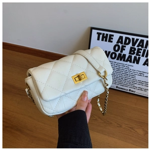 Détail de la texture en cuir blanc matelassé et du fermoir doré du sac bandoulière