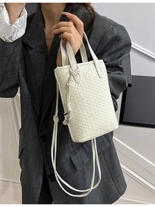 Borsa tote intrecciata beige con ciondolo a cuore su completo con blazer grigio