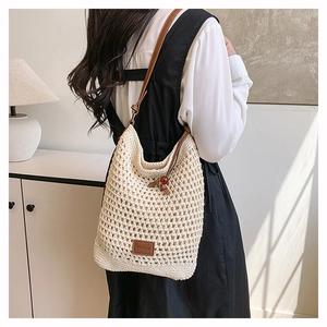 Gros plan du sac fourre-tout tissé crème avec bandoulière en cuir et détail du logo