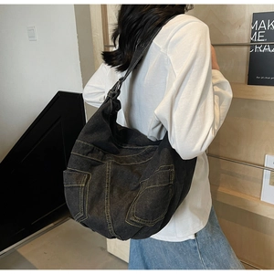 Detail of black denim messenger bag featuring contrast yellow stitching and utility pockets