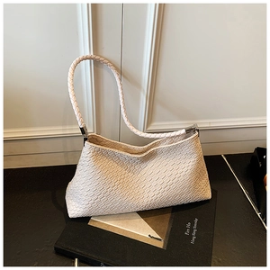 Détail du sac hobo tissé blanc crème avec anse en corde épaisse sur un livre