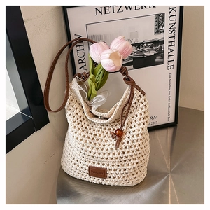 Détail du sac cabas tissé main montrant la texture crème et la poignée en cuir brun