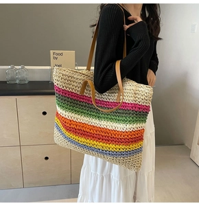 Detailed texture of multi-color woven straw tote bag with brown leather handles